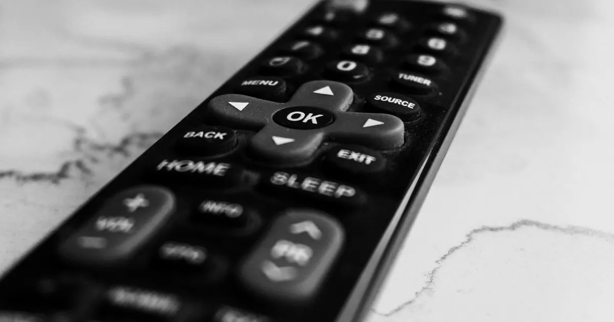 Set-top box remote control with navigation buttons on a marble surface — ViviMate on MAG box